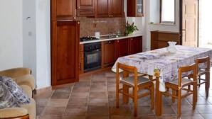 A kitchen with wooden cabinets, a stove, and a dining table with chairs. - Beautiful private villa for 4 people with WIFI, TV, terrace and pets allowed (Picciano)