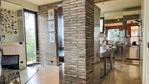 Een moderne keuken met roestvrijstalen apparatuur, een accentmuur van baksteen en een glazen eethoek.