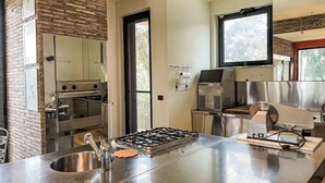 Een moderne keuken met een gasfornuis, roestvrijstalen apparatuur en een accentmuur van baksteen.