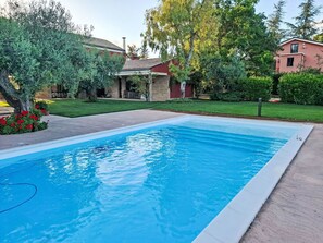 Une piscine rectangulaire à l’eau d’un bleu limpide, entourée d’une terrasse en béton.