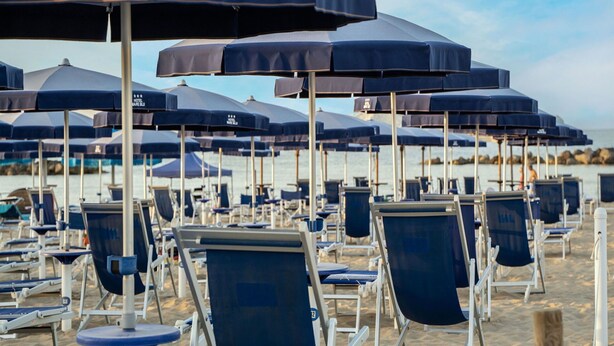 Rows of beach chairs and umbrellas on a sandy beach.