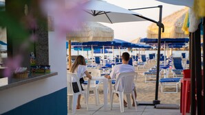 A beachside cafe with outdoor seating and umbrellas.