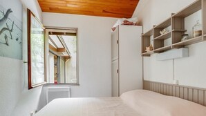 Een slaapkamer met een groot bed, een raam, een kledingkast en inbouwkasten met decoratieve objecten.