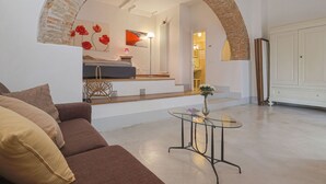 A modern living room with a sofa, a glass table, and a brick archway leading to a bedroom. - Beautiful apartment in villa with WIFI, pool, A/C, TV, terrace, pets allowed and panoramic view (Cennina)