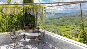 A terrace with a table and chairs, a pergola with hanging vines, and a scenic view of a valley. - Beautiful apartment in villa with WIFI, pool, A/C, TV, terrace, pets allowed and panoramic view (Cennina)