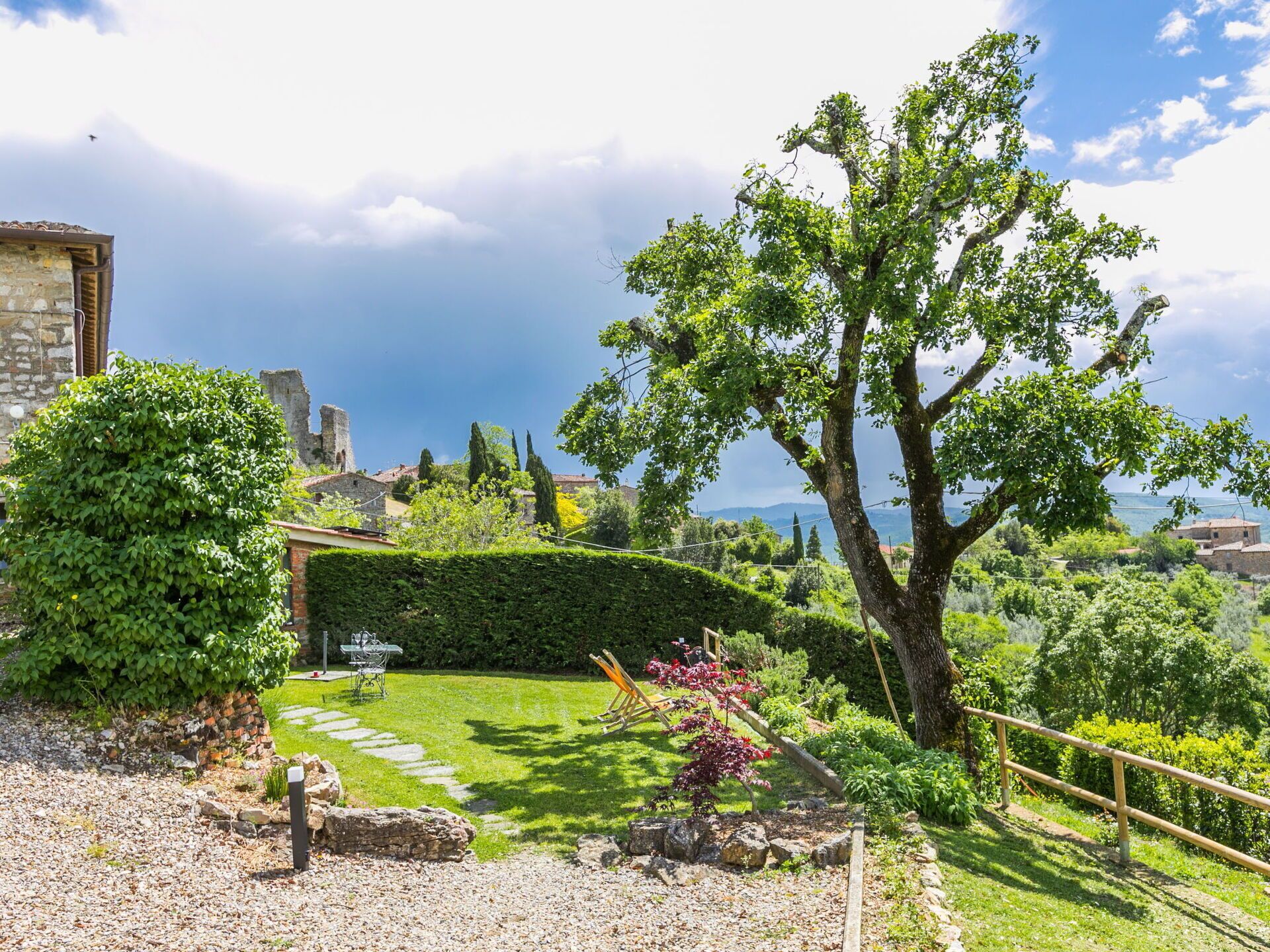 Un jardín con muro de piedra, un árbol y vista al mar.