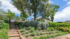 Una escalera de piedra que lleva a una casa con un muro de piedra y un jardín con diversas plantas.
