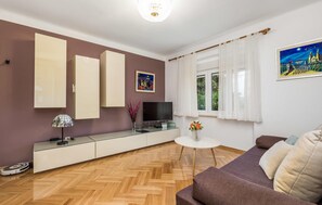 Relax in this stylish living room with a large flat-screen TV, comfortable sofa, and beautiful vase of flowers.