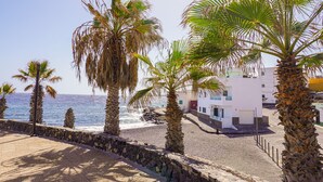 A coastal building with a stone wall and palm trees, overlooking the sea. - Las Eras - The House in front of the Sea (Arico)