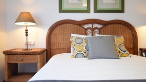 A neatly made bed with patterned pillows, a wicker nightstand with a lamp, and two framed pictures on the wall. - Las Eras - The House in front of the Sea (Arico)