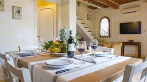 Comedor con una mesa dispuesta para cuatro personas, una botella de vino y un frutero.