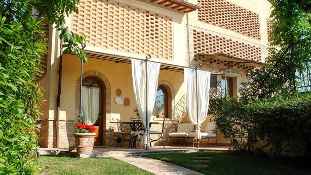 Edificio de dos plantas con un patio cubierto y mobiliario exterior.