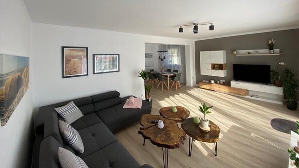 Een moderne woonkamer met een bank, salontafels en een televisie.
