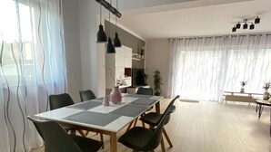 Een eethoek met een lange tafel, zwarte stoelen en hanglampen.