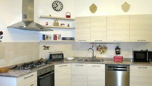A modern kitchen with a gas stove, oven, microwave, and dishwasher. There are wooden cabinets, a stainless steel range hood, and a clock on the wall. - Nice apartment in villa for 7 people with WIFI, A/C, terrace and pets allowed (Pomarance)