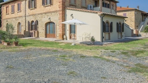 A two-story stone building with a tiled roof, arched windows, and a gravel driveway. - Nice apartment in villa for 7 people with WIFI, A/C, terrace and pets allowed (Pomarance)