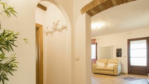 A hallway with a wooden door, a beige sofa, and a patterned rug. - Nice apartment in villa for 7 people with WIFI, A/C, terrace and pets allowed (Pomarance)