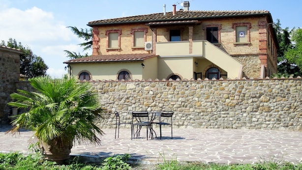 A two-story house with a stone wall and a tiled roof. - Nice apartment in villa for 7 people with WIFI, A/C, terrace and pets allowed (Pomarance)