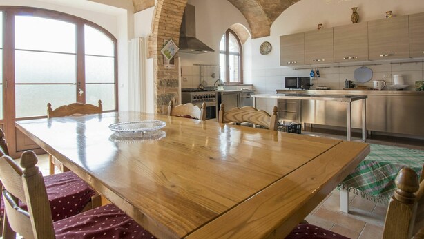 Uma sala de jantar espaçosa com uma mesa de madeira comprida, cadeiras e vista para o mar através de grandes janelas.