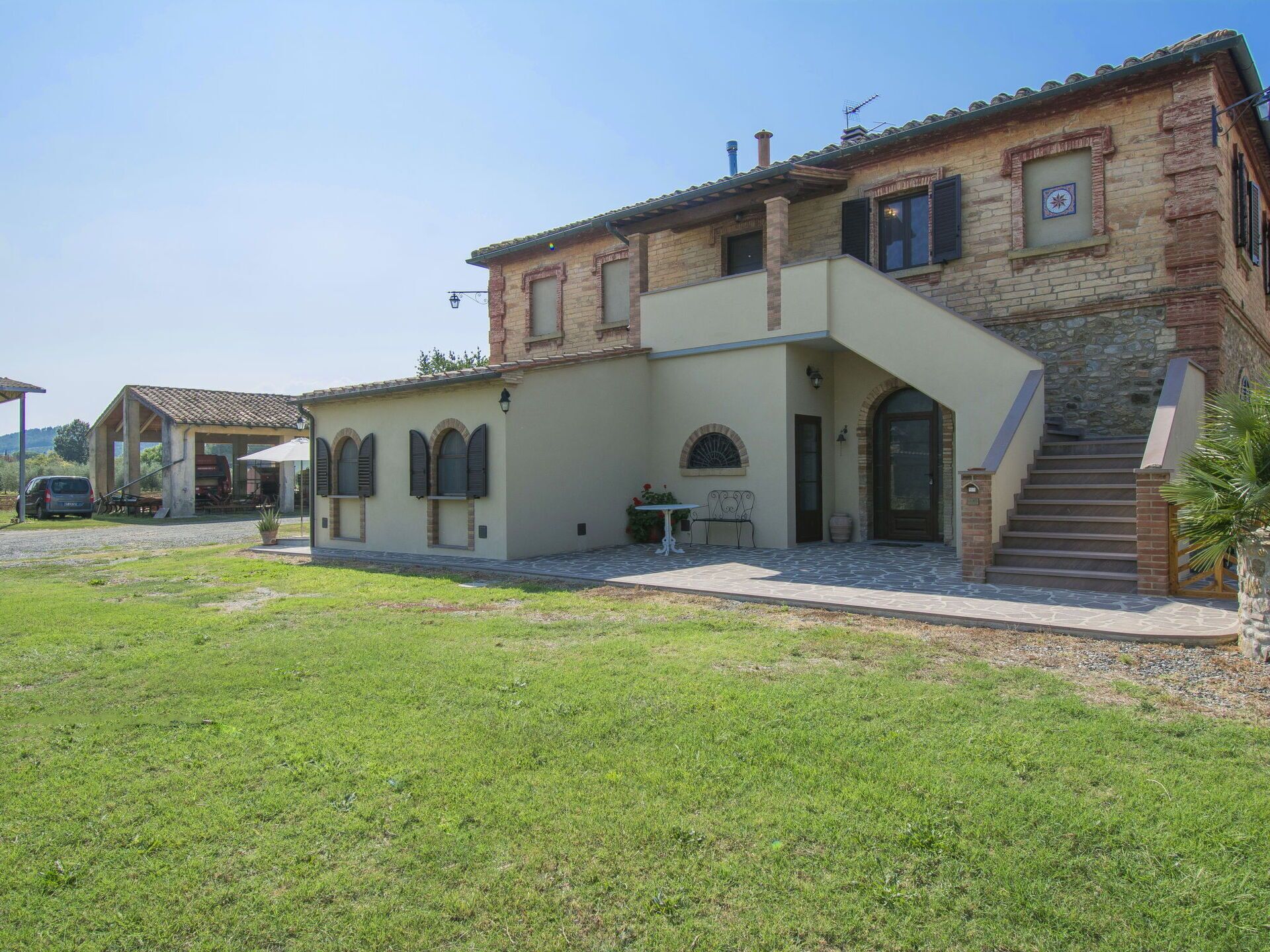 A two-story building with a stone facade, a covered patio area, and a staircase leading to the upper floor.