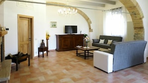Uma sala de estar com lareira, televisão, sofá e mesa de centro.