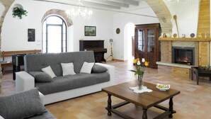 Uma sala de estar com um sofá cinzento, uma mesa de centro de madeira, uma lareira e uma grande porta arqueada.