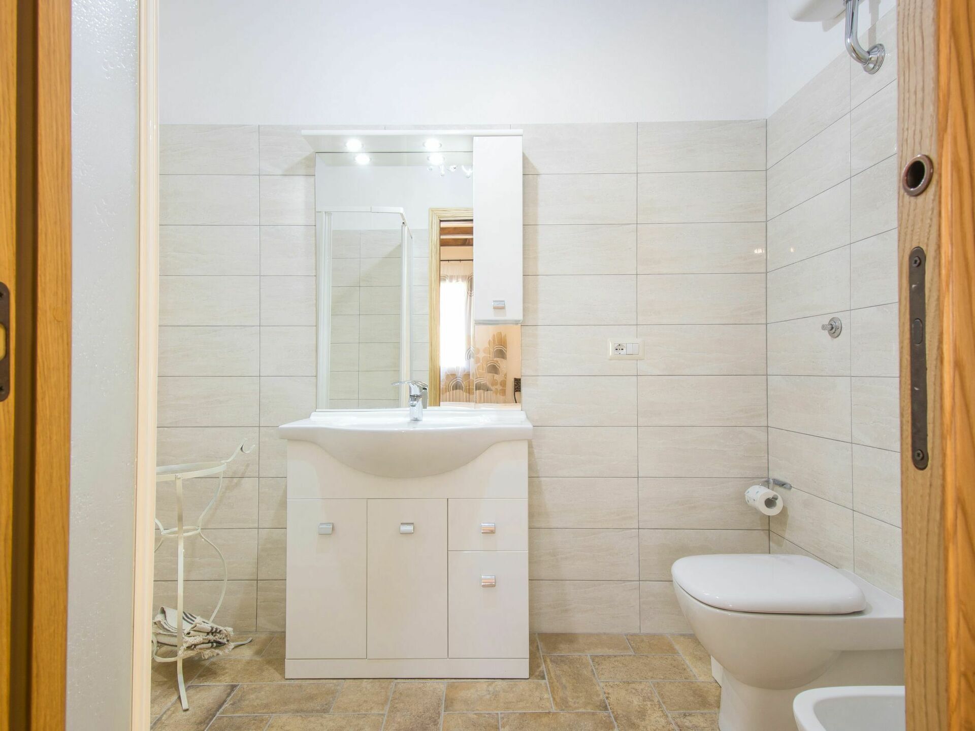 Un bagno con un lavandino, uno specchio e un water bianchi.