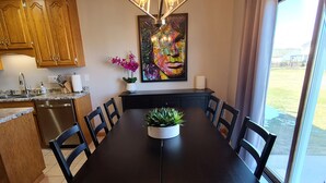 Un comedor con una gran mesa, sillas, una araña, armarios de madera, un lavabo y una ventana con vistas.