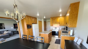 Una cocina moderna con armarios de madera, una isla central y un comedor con una mesa y sillas negras.