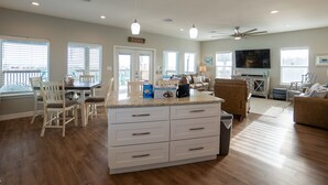 Amplia sala de estar con isla de cocina, mesa de comedor y asientos.