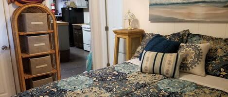 Ein Schlafzimmer mit einem gemusterten Bettbezug, einer Fischdekoration, einer Leiter und einem Gemälde von Wellen.
