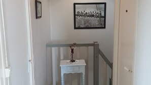 Ein Flur mit einem hellblauen Konsolentisch, einem schwarz-weißen gerahmten Foto an der Wand und einer weißen Tür auf der rechten Seite.