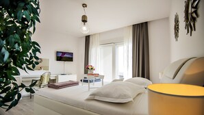 Een moderne hotelkamer met een bed, bureau, stoel, televisie en een potplant.