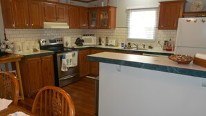 A kitchen with wooden cabinets, a stove, a microwave, and a sink. - Quiet 3 bedroom, 2 Bath Home located within 1/2 mile of ferry to Cape Lookout  (Harkers Island)