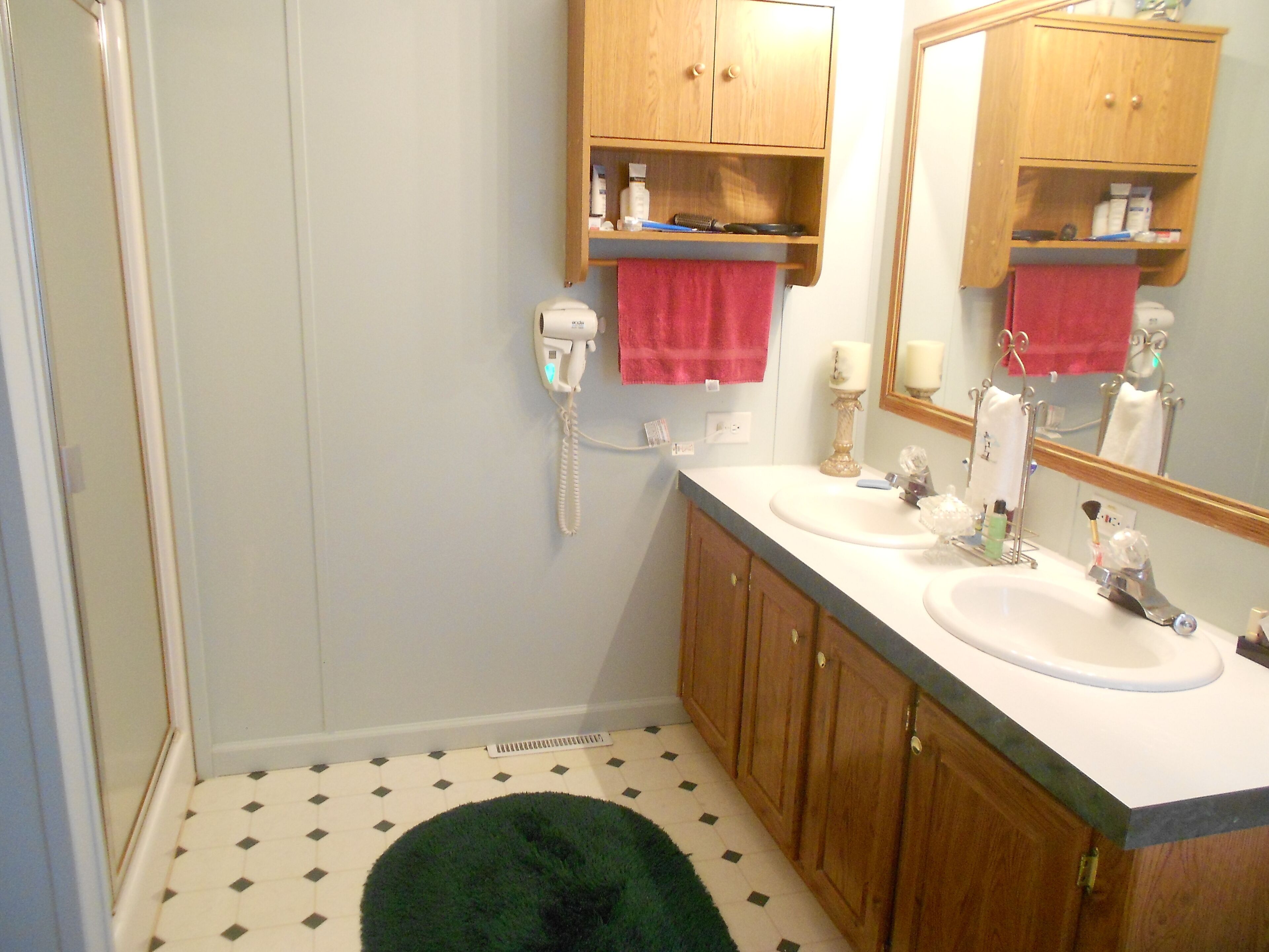 A bathroom with two sinks, wooden cabinets, a mirror, a telephone, and a patterned floor.