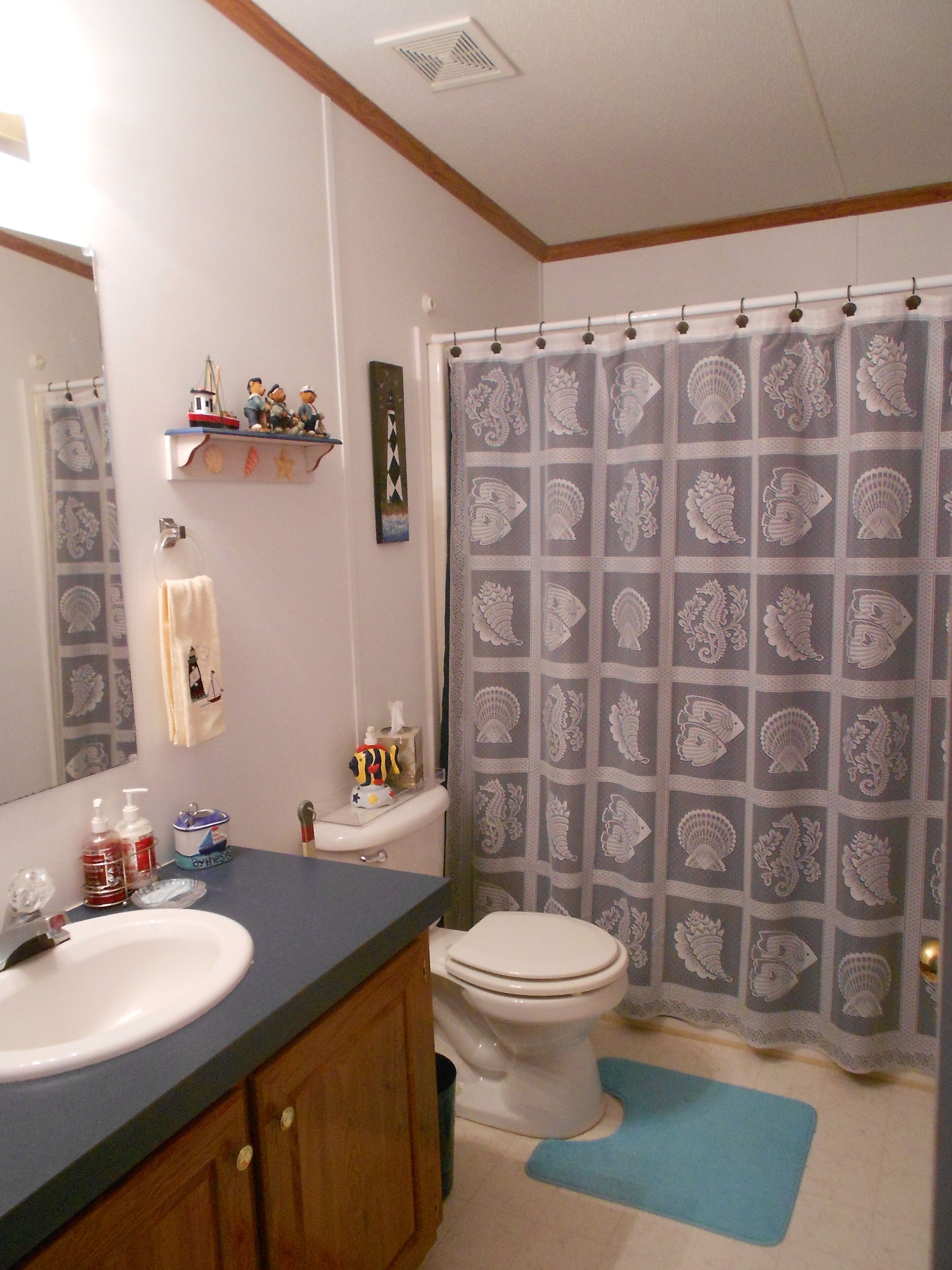 A bathroom with a sink, toilet, and shower curtain with a seahorse pattern.