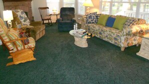 A cozy living room with a fireplace, a sofa, a chair, and a coffee table. - Quiet 3 bedroom, 2 Bath Home located within 1/2 mile of ferry to Cape Lookout  (Harkers Island)