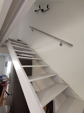 A white staircase with a handrail, leading to an upper floor.