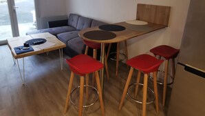 A modern living space with a sofa, a small table, red bar stools, and a refrigerator. - Duplex T3 Anglet - Parking / Terrace / Pool - (Anglet)