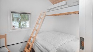 Een stapelbed met een houten ladder, een raam met uitzicht op bomen en sneeuw, en een witte muur.
