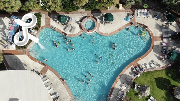 Una gran piscina al aire libre con varias pistas de natación y un tobogán de agua.