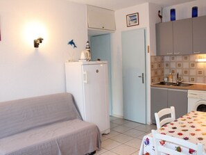 Un espace de vie compact comprenant un coin cuisine, un petit coin repas et un lit.