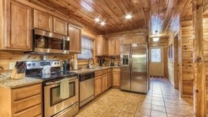 A wooden cabin-style kitchen with built-in appliances, a tiled floor, and a long countertop. - Day Dreamer by Beyond Expectations: Cozy Cabin w/ Views & Outdoor Fun (Gatlinburg)