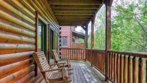A wooden log cabin with a porch featuring rocking chairs and a wooden railing. - Day Dreamer by Beyond Expectations: Cozy Cabin w/ Views & Outdoor Fun (Gatlinburg)