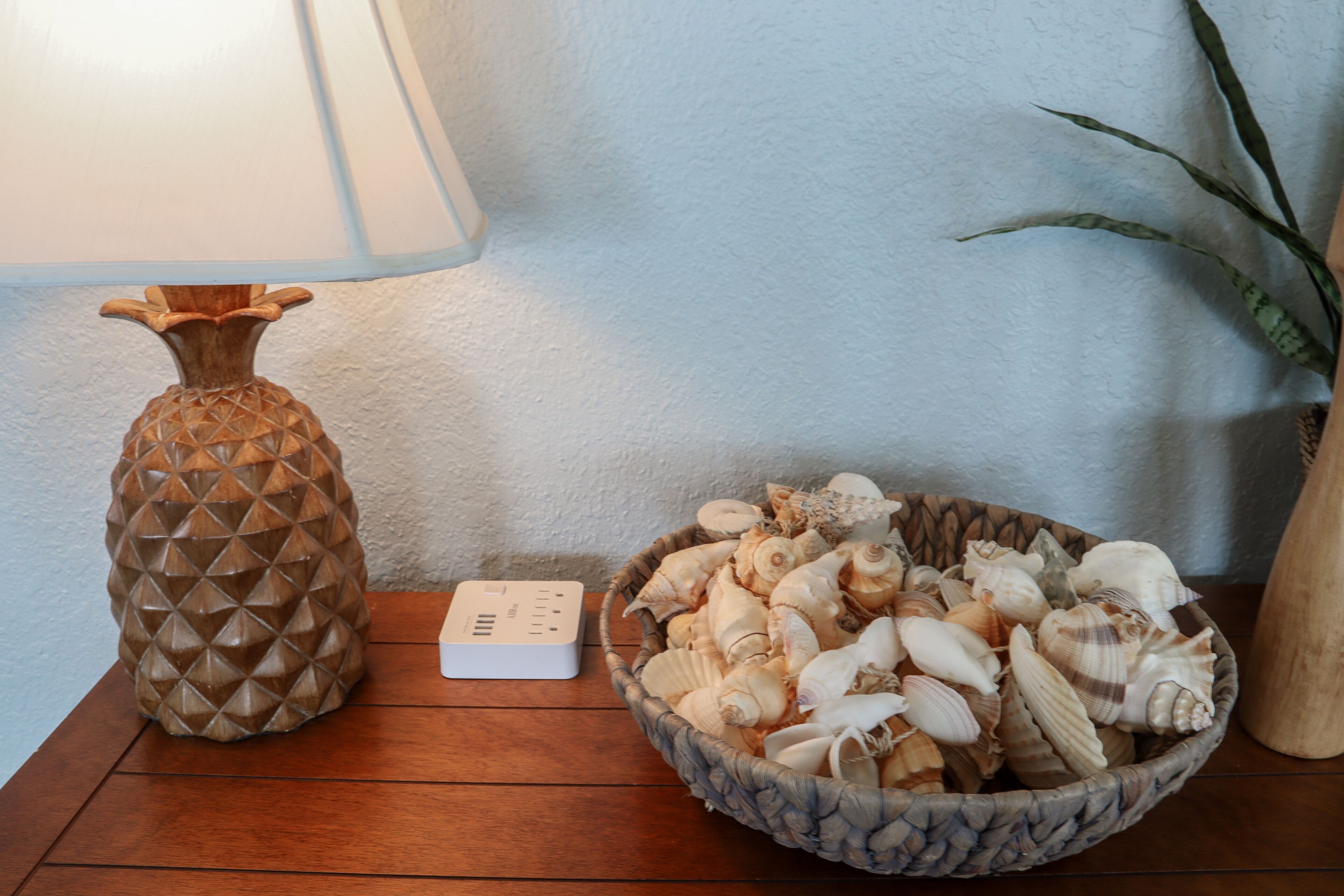 Un tavolo di legno con una lampada decorativa e una ciotola di conchiglie.