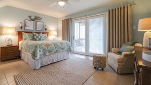 A bedroom with a bed, bedside tables, a chair, a lamp, and a ceiling fan.