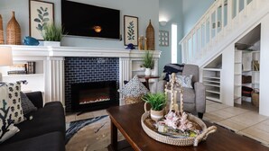 A living room with a fireplace, a sofa, a coffee table, and a staircase.