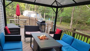 A covered outdoor deck with blue cushioned seating, a grill, and a fire pit. - Private Canoes & Charming Lake House  (Long Pond)
