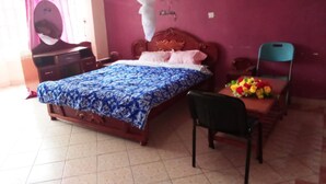 Une chambre à coucher avec un lit, une chaise, un bureau et une table ornée de fleurs.