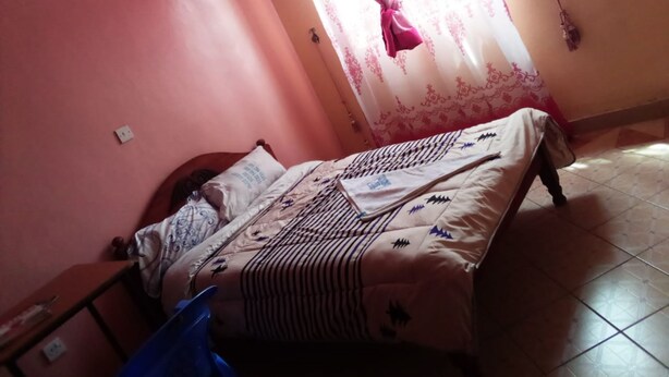 Une chambre avec un lit, une table de chevet et une fenêtre avec des rideaux.